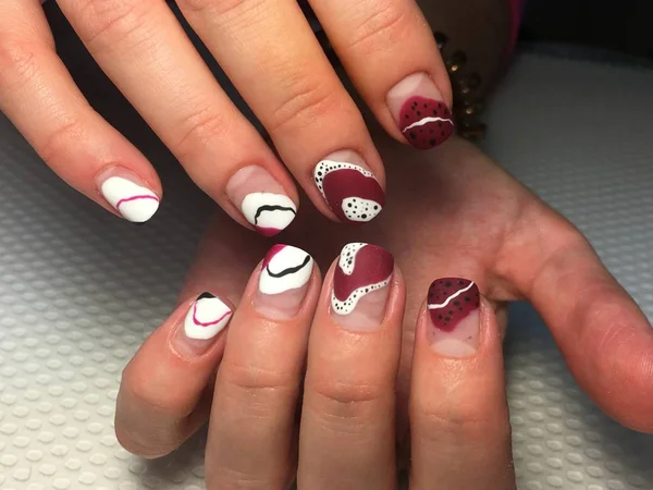 Manicure na moda e elegante com um design vermelho e pontos brancos — Fotografia de Stock