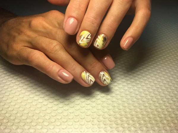 Modny i stylowy żółty manicure ze złotym liściem i białym wzorem — Zdjęcie stockowe