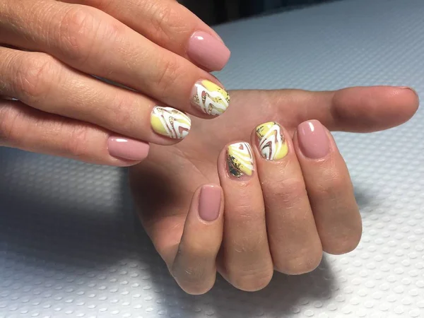 Trendy and stylish yellow manicure with gold leaf and white design — Stock Photo, Image