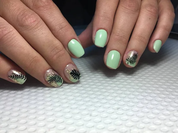 Modny zielony manicure ze stylowym designem i czarnym liściem — Zdjęcie stockowe
