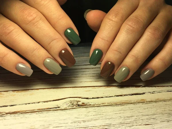 Модный коричневый маникюр на коротких ногтях с серым и зеленым — стоковое фото