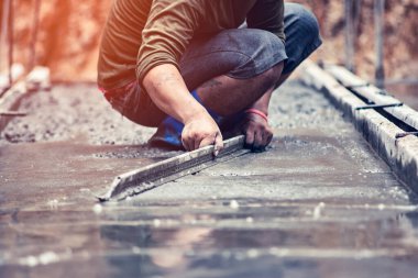 İşçiler beton yüzeyi pürüzsüz ayarlıyorlar.