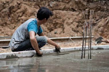 İşçiler beton yüzeyi pürüzsüz ayarlıyorlar.