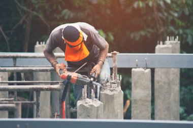 İşçiler beton delmek için darbe matkabı kullanıyorlar. Güneş ışığı altında