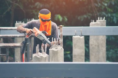 İşçiler beton delmek için darbe matkabı kullanıyorlar. Güneş ışığı altında