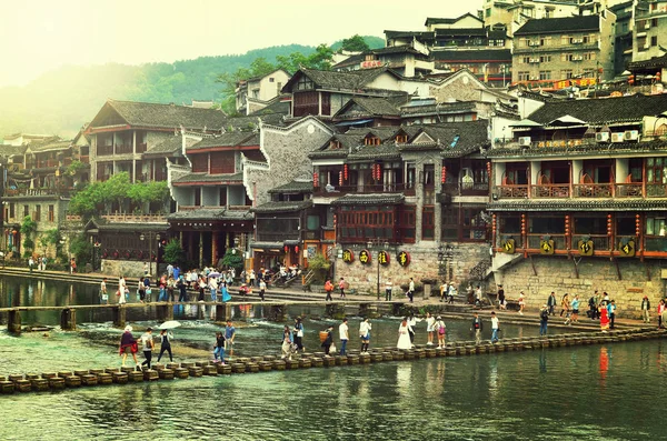 Fenghuang, China - 15 de maio de 2017: Pessoas que cruzam a famosa ponte sobre o rio Tuojiang no centro de Fenghuang no dia chuvoso . — Fotografia de Stock