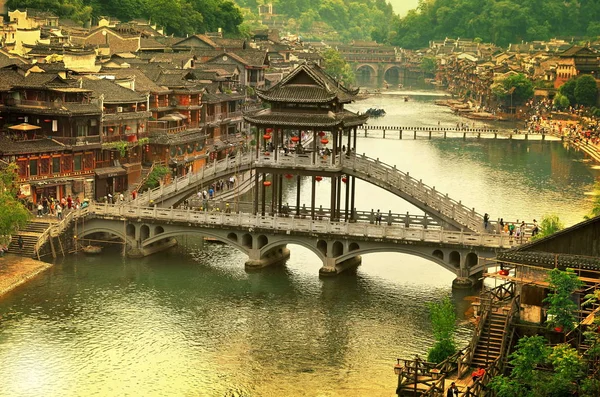 Fenghuang, China - 14 de mayo de 2017: Gente alrededor de la orilla del río en el puente Phoenix Hong en Fenghuang — Foto de Stock