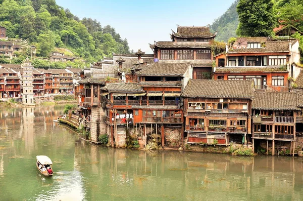 Fenghuang, China - 15 de mayo de 2017: Antiguo edificio con gente en el patio de comidas a orillas del río cerca del puente Phoenix Hong en Fenghuang — Foto de Stock