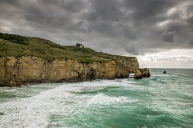 Pasifik Okyanusu tünel beach, Dunedin, Yeni Zelanda, kumlu kayalıklarla karşılar