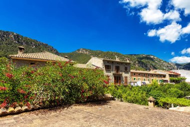 Eski binalar, çiçek açan bitkiler ve dağlar şehirde Valdemossa, Mallorca, İspanya