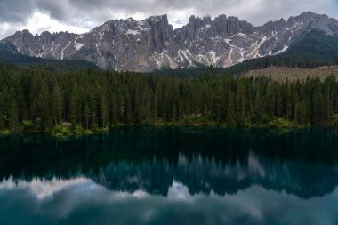 İtalya, Güney Tyrol Dolomitleri 'nden Carezza' nın görkemli küçük alp gölü kristal suyuyla süslü yeşil orman.