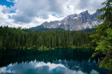 İtalya, Güney Tyrol Dolomitleri 'nden Carezza' nın görkemli küçük alp gölü kristal suyuyla süslü yeşil orman.