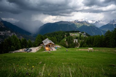 İtalya, Güney Tyrol 'daki Dolomitlerin dağlarının ve orman evlerinin harika manzarası.