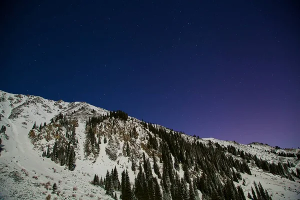 Mountains at night. View of mountain range night sky with stars and constellation of the orion in the full moon.