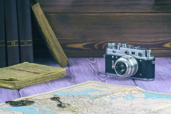 Retro-Stil. alte Bücher und eine Landkarte auf dem Tisch. Filmkamera und eine Handvoll Münzen. — Stockfoto