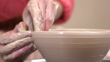 Bir clayware çıkrık potter's üzerinde şekillendirme bir çamurlu elleri closeup yan görünüm.
