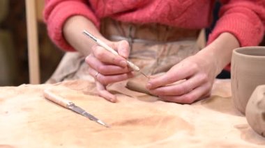 Ham kil parçası üzerinde bir bıçak aracını kullanarak bir dekorasyon koyarak bir kız ustası closeup.