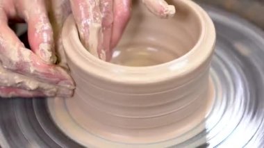 Bir clayware potter's çıkrık oluşturma bir çamurlu elleri closeup.