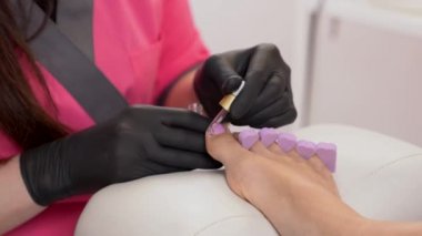 Kütikül yağ uygulanıyor. Kadın ayaklar ayak parmağı ayırıcıları ile closeup. Pedikür tedavi.