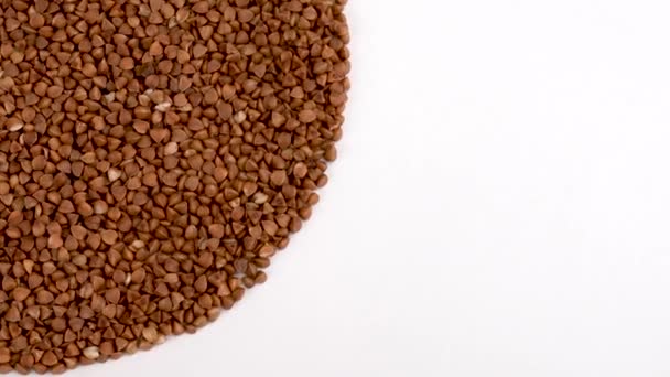 Half frame circle shaped heap of toasted buckwheat rotating on turn table. Isolated on white. Loopable. Close up macro. View from above/overhead. — Stock Video