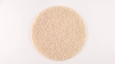 Daire çiğ beyaz pirinç dönen yığın şeklinde. Beyaz izole. Dan yukarıda/ek yükünü görüntüleyin. Loopable. Makroyu kapat.