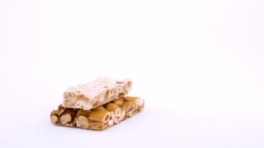 Düzenlenen geleneksel İspanyol tatlı Turron yarım çerçeve. Üzerinde beyaz arka plan üzerinde döner. İzole. Makroyu kapatın. Loopable.