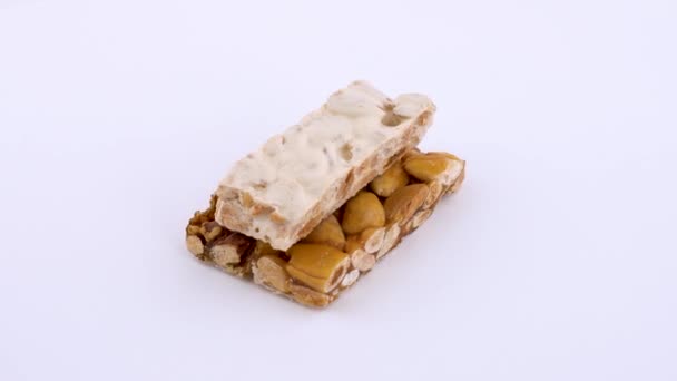Turron - traditionelles Dessert in Spanien, das auf einem weißen Drehtisch rotiert. isoliert auf weißem Hintergrund. Schlupflöcher. Nahaufnahme Makro. — Stockvideo