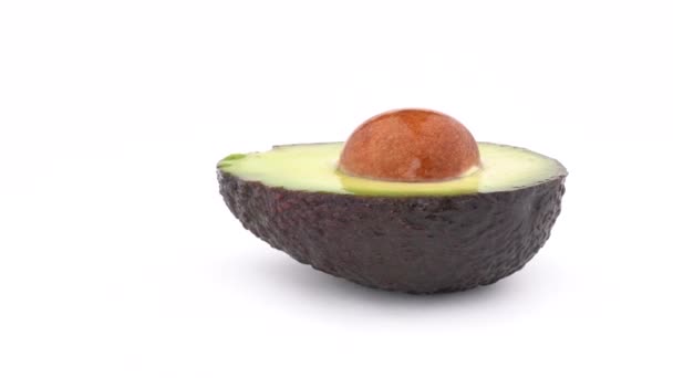 Geschnittene frische Avocado-Haas mit einem Samen, der sich auf dem Drehtisch dreht. isoliert auf weißem Hintergrund. Schlupflöcher. Nahaufnahme Makro. — Stockvideo