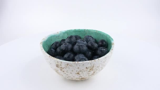 充满新鲜蓝莓的杯子在白色背景上旋转。孤立。Loopable。特写. — 图库视频影像