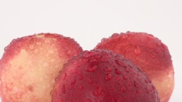 Gros plan macro de trois nectarines fraîches avec des gouttes d'eau tournant sur une table tournante . — Video