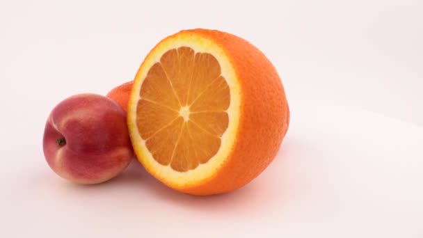 Fruta naranja fresca y jugosa, mandarina y nectarina girando en el plato giratorio. Aislado sobre fondo blanco. De cerca. . — Vídeo de stock