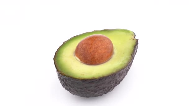 El aguacate crudo Haas rebanado con una semilla gira lentamente sobre la mesa giratoria. Aislado sobre fondo blanco. Primer plano macro . — Vídeos de Stock