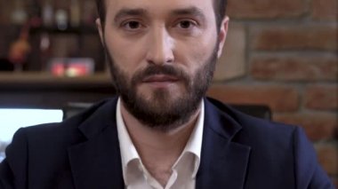 İyi giyimli, kendine güvenen genç sakallı lookig güvenle kameraya adamdır. Portre.