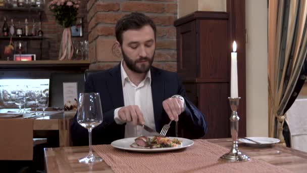 Großaufnahme eines Mannes mit Bart, der am Tisch im Restaurant sitzt. Fleischgericht essen und gutes Essen genießen. — Stockvideo