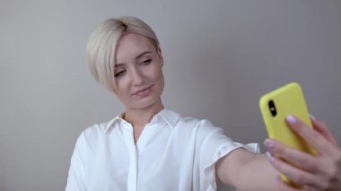 Kız kolunu uzanmış selfie yapar. Telefon sarı bir durumdur.