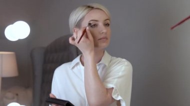 Genç sarışın bir kadın portresi göz gölgeler ve bir fırça onun elinde tutar. O kapaklarını üzerinde bir gölge koyar.