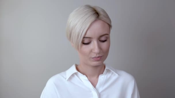 Молодая блондинка смотрит в камеру и наносит порошок на лицо с помощью большой белой кисти основания . — стоковое видео