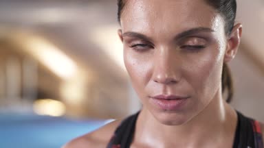 Doğrudan gözlerinin içine bakarak güzel kadın portresi kapatın. Arka planda fitness stüdyosu.