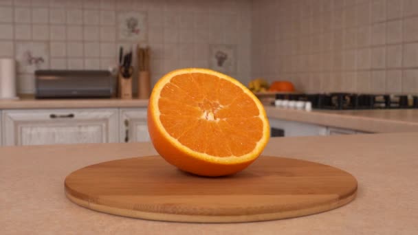 Zblízka se plátky oranžové ovoce. Polovina oranžová. Otočná kamera s bílou kuchyni na pozadí. Dolly-shot. — Stock video