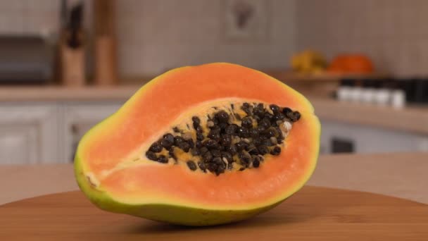 Nahaufnahme von in Scheiben geschnittenen Papayafrüchten. die Hälfte der Papaya. drehbare Kamera mit weißer Küche im Hintergrund. Dollyshot. — Stockvideo