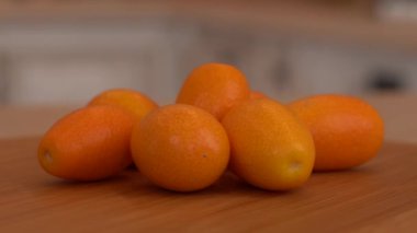 Birkaç bütün kumquats kapatın. Fotoğraf makinesi ve arka plan üzerinde beyaz mutfak ile döner. Dolly-shot.