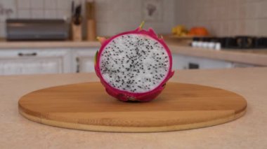 Yarım dilim taze dragon meyve (pitahaya). Fotoğraf makinesi ve arka plan üzerinde beyaz mutfak ile döner. Dolly-shot.