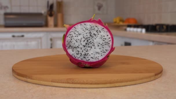 Meia fatia de fruta fresca de dragão (pitahaya). Câmera rotativa com cozinha branca no fundo. Tiro de boneca . — Vídeo de Stock