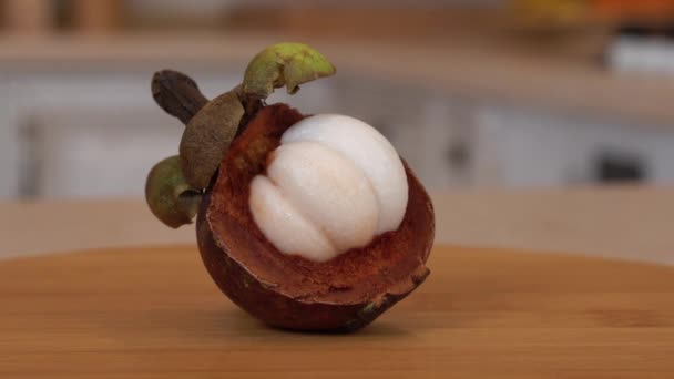 Macro close-up. De helft van de paarse mangosteen. Draaiende camera met witte keuken op de achtergrond. Dolly-shot. — Stockvideo