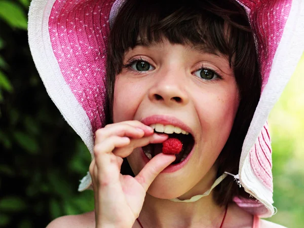 Девушка в шляпе ест малину . Лицензионные Стоковые Фото