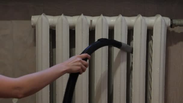 女性は掃除機による暖房のラジエーターのセクション間のクリーニング実施します — ストック動画