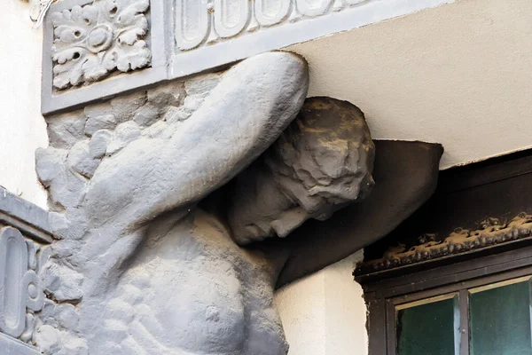 Sculpture of a man on the facade of an old building close-up.