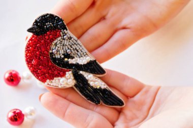 Bir kadın elinde ispinoz denen boncuklu bir kuş tutuyor..