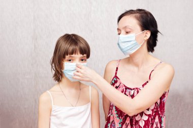 Yüzlerinde koruyucu tıbbi maskeler olan anne ve kız..