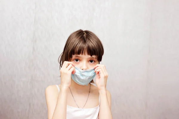 Kız koruyucu tıbbi maskesini yüzüne takıyor..